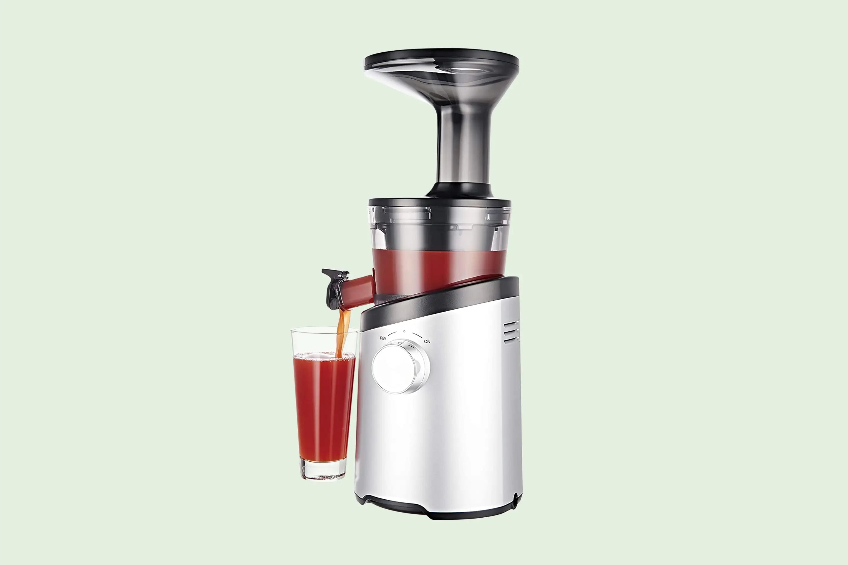 A sleek masticating juicer extracting vibrant green juice from fresh vegetables, showcasing its slow and powerful cold-press technology for maximum nutrition.