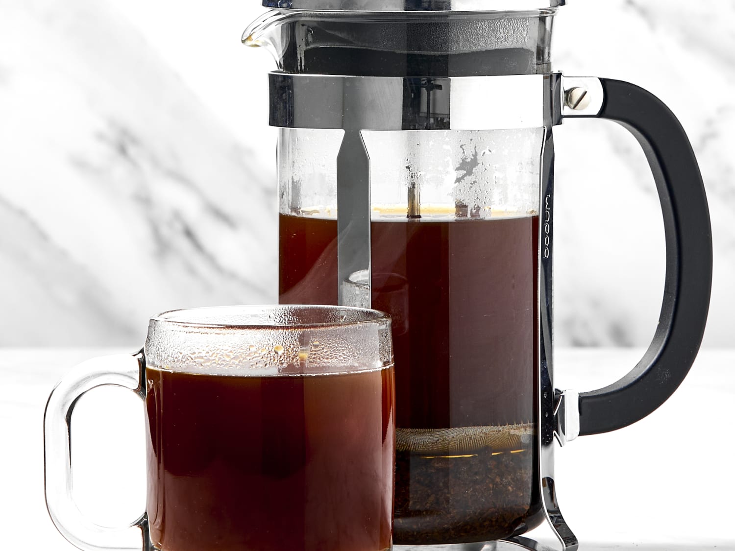 A freshly brewed cup of French press coffee with a coarse grind, ready to be poured into a mug.